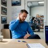 Dans son bureau encombré, le patron du garage passe en revue ses factures, entouré de papiers et de dossiers.
