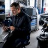 Un technicien consulte sa tablette dans le bureau de l’atelier automobile.