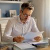 Un homme examine attentivement son contrat d’assurance contre la casse de vitrages.