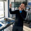 Un spécialiste examine attentivement un pare-brise dans son atelier.
