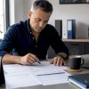 Le responsable de l’atelier passe en revue les bons de réparation assis à son bureau.