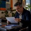 Un homme examine attentivement des documents juridiques à son bureau.