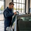 Un technicien procède à l’inspection du toit panoramique d’une voiture à l’intérieur de l’atelier.