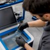 Un technicien procède à l’archivage numérique des dossiers de réparation de vitrages.