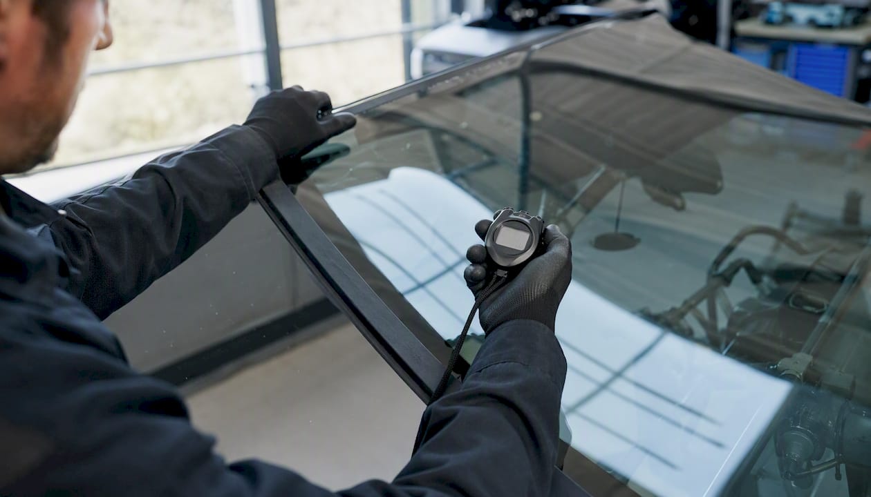 Technicien lançant un chronomètre lors de l'installation d'un pare-brise