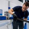 Technicien contrôlant un vitrage dans un atelier automobile