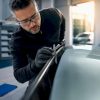 Technicien vérifiant l'ajustement d'un vitrage automobile